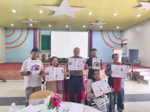 A total of 6 people are standing in front of camera. All of them are showing the financial literacy handbook towards the camera.