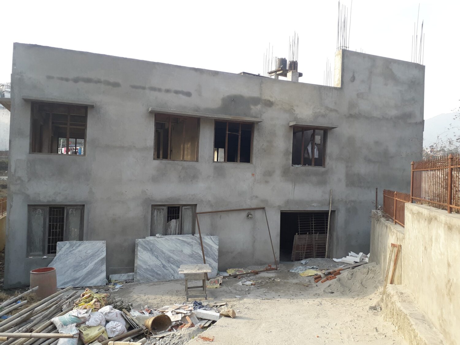 This is a picture of NDWA Rehabilitation center in Budanilkantha. The building is two-storied and freshly plastererd. The windows and doors haven't been installed and the painting is also not done in the building.