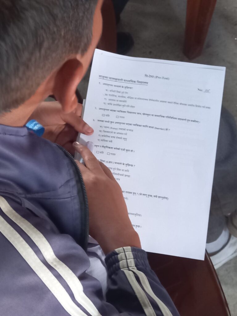 An adolescent boy filling pre- test questionnaire during a session on disability and gender-based violence.