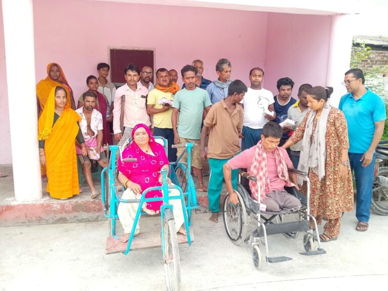 The participants are looking towards the camera, posing for a group photo. The two participants in the front row are sitting in wheelchairs.